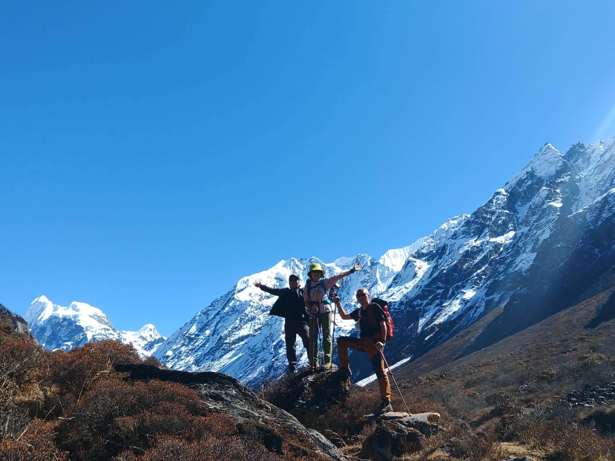 A trekking group standing together beneath snow-covered mountains.