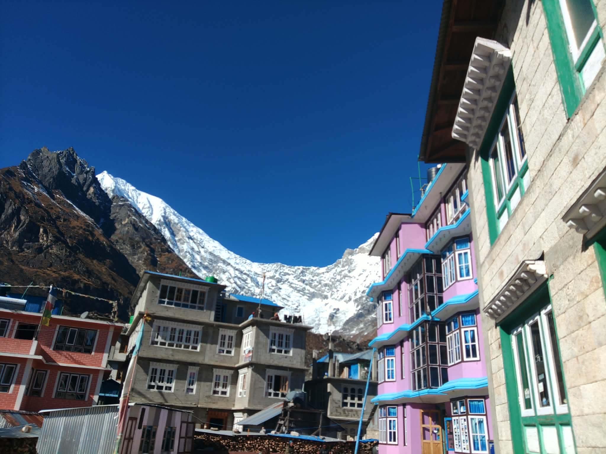 Colourful buildings lining a village street beneath snowy mountains.