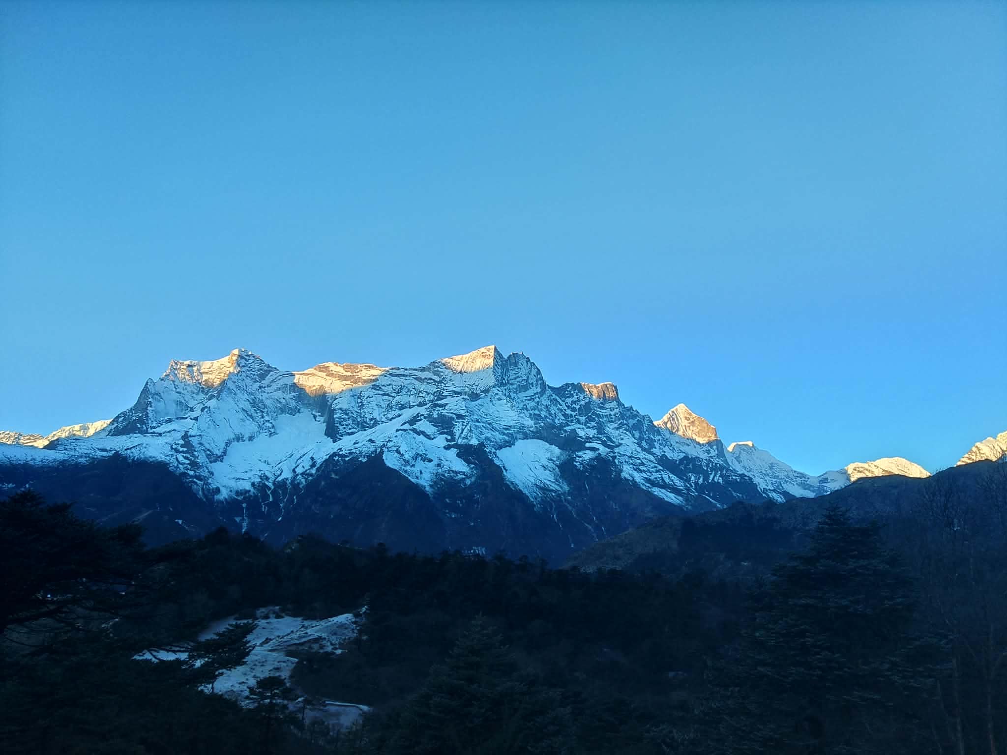 First sunlight touching a snowy mountain range above the forest
