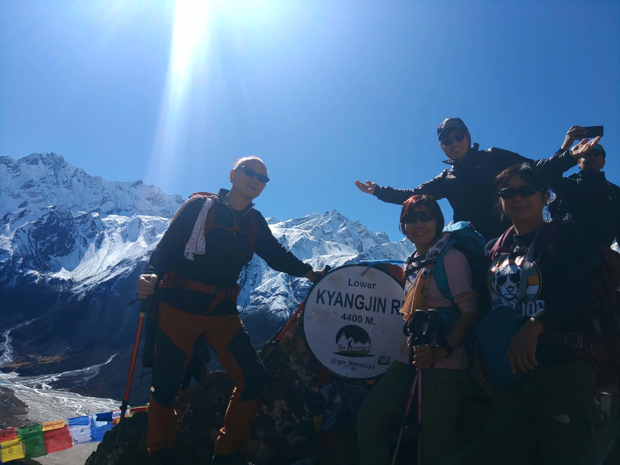 Trekkers resting together on a hillside beneath the Himalayas